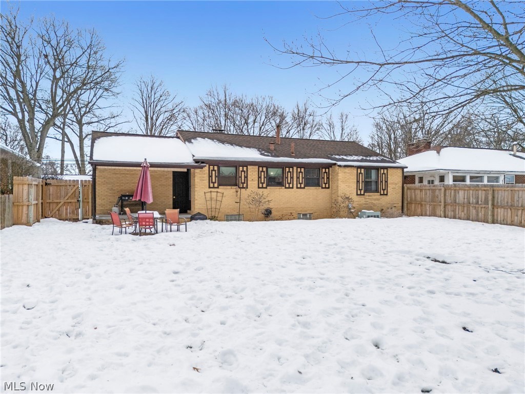 3517 26th Street Northwest Canton, OH 44708 - Photo 16 of 22 Snow covered back of property featuring brick siding, a patio area, a gate, a chimney, and outdoor dining area