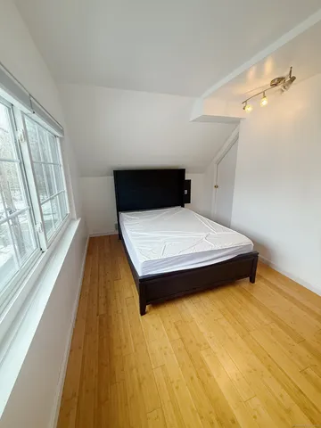 a bedroom with a bed and wooden floor