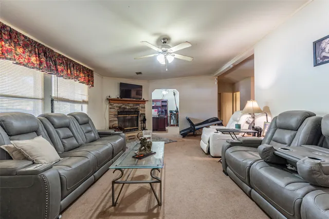 a living room with furniture a fireplace and a ceiling fan