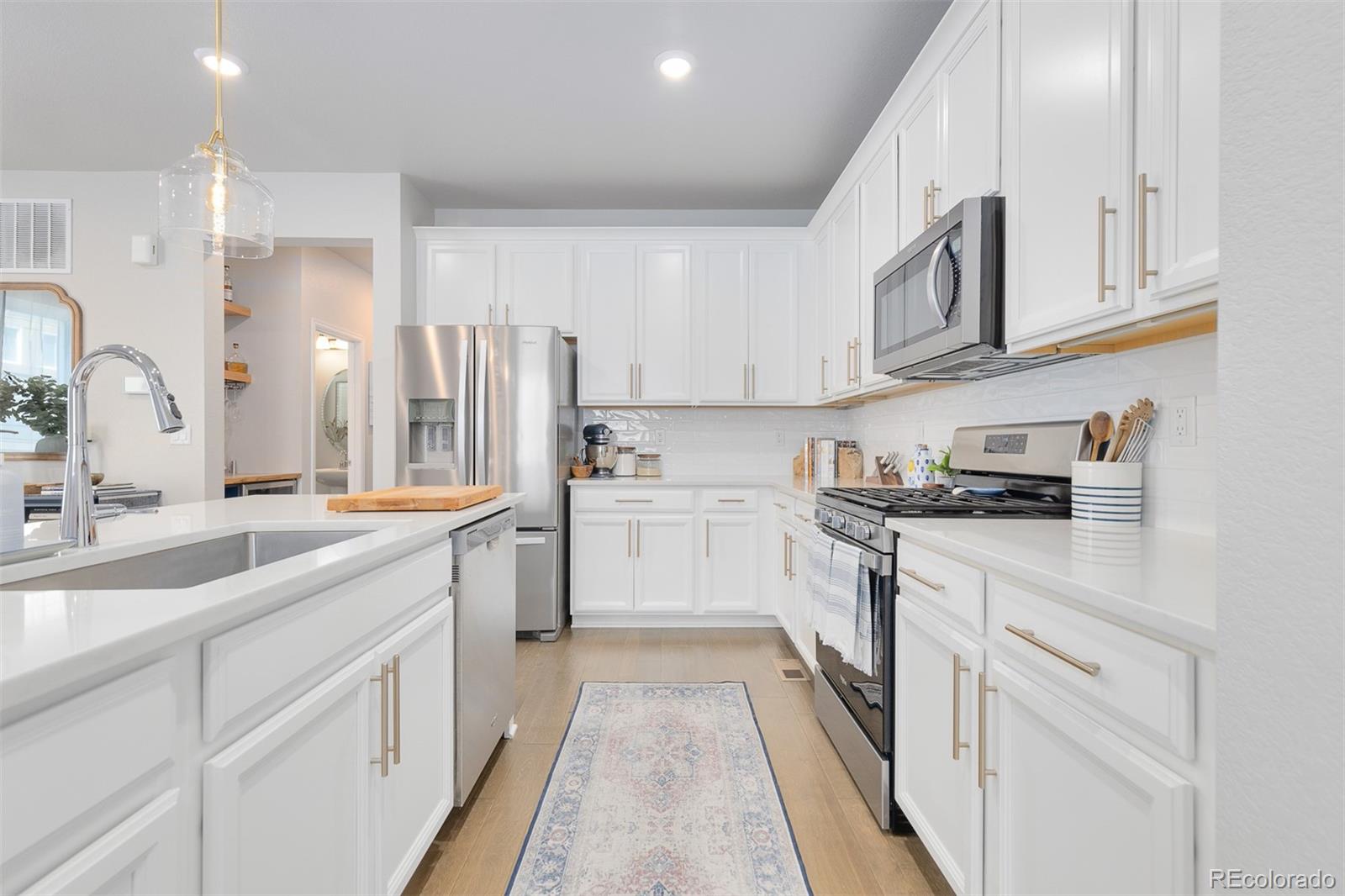 7199 Othello Street Castle Pines, CO 80108 - Photo 4 of 28 a kitchen with granite countertop white cabinets and white appliances