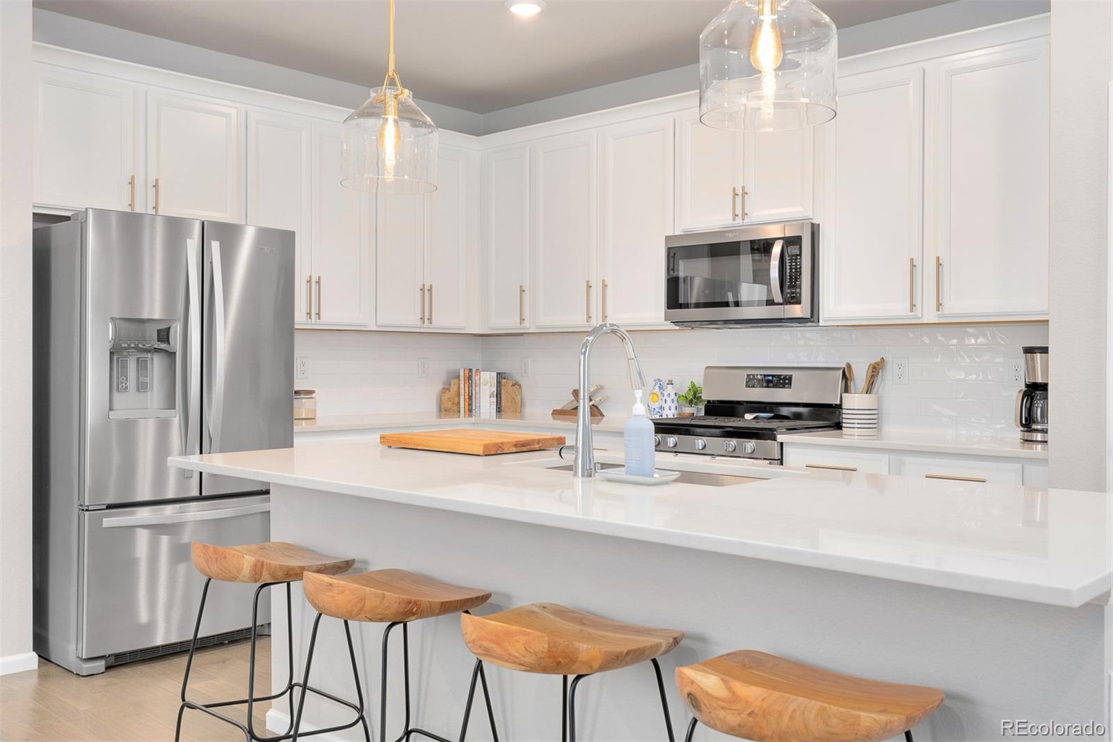 7199 Othello Street Castle Pines, CO 80108 - Photo 6 of 28 a kitchen with stainless steel appliances white cabinets a sink and a stove