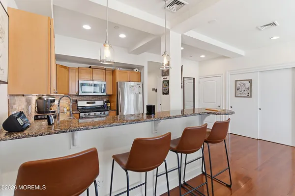 a kitchen with stainless steel appliances a dining table chairs sink and wooden cabinets