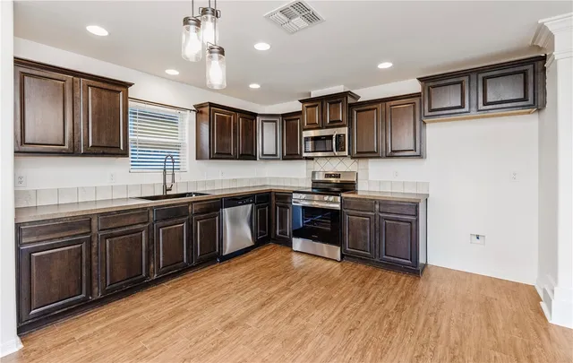 a kitchen with stainless steel appliances granite countertop a stove a sink and a microwave
