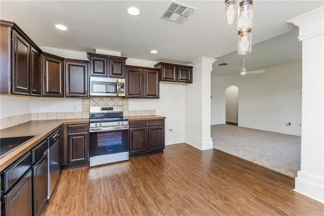 a large kitchen with stainless steel appliances granite countertop a stove a sink dishwasher and a refrigerator with wooden floor