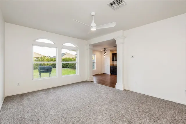 an empty room with large windows and a ceiling fan