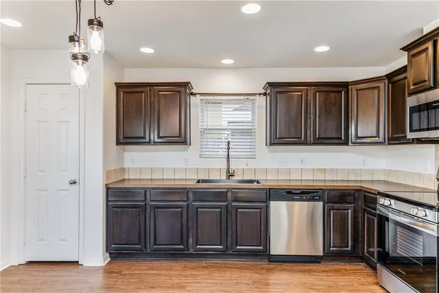 a kitchen with stainless steel appliances granite countertop wooden cabinets a sink and dishwasher