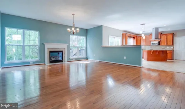 an empty room with wooden floor fireplace and windows