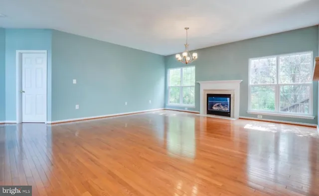 an empty room with wooden floor fireplace and windows