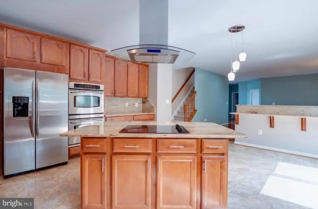 a kitchen with stainless steel appliances kitchen island granite countertop a refrigerator and a sink