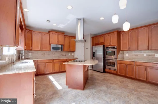 a kitchen with stainless steel appliances granite countertop wooden cabinets a sink dishwasher a stove a refrigerator and island with wooden floor
