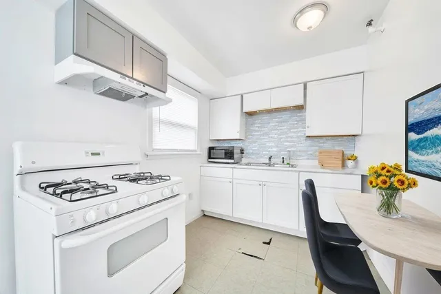 a kitchen with stainless steel appliances a white stove top oven a chimney a sink and a stove