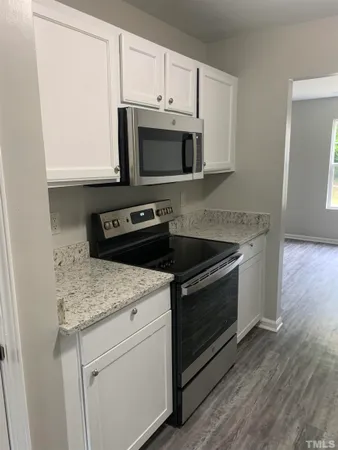 a kitchen with granite countertop cabinets stainless steel appliances and wooden floor