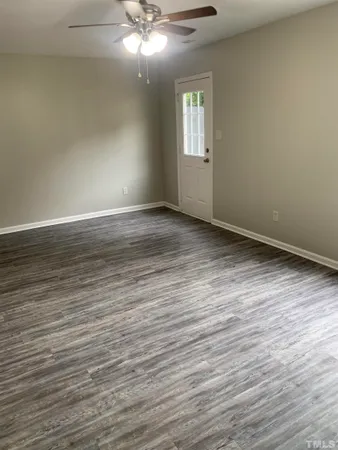 a view of an empty room with wooden floor and a window
