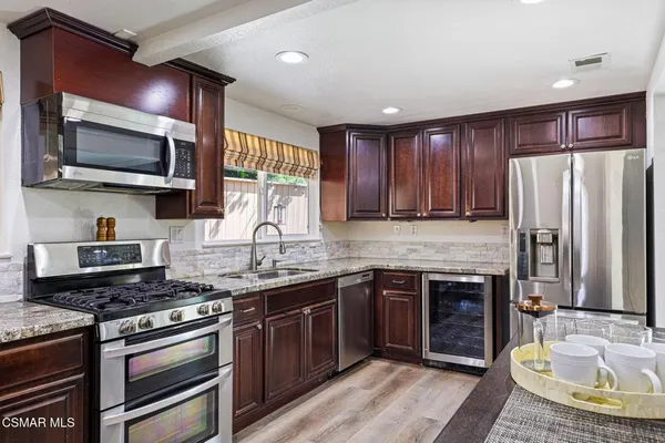 a kitchen with stainless steel appliances granite countertop a stove top oven a sink dishwasher a refrigerator and a microwave