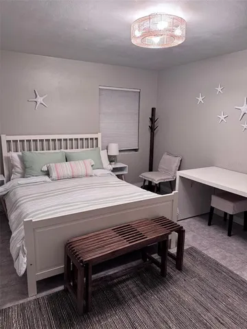 a bedroom with a bed a table and painting on the wall