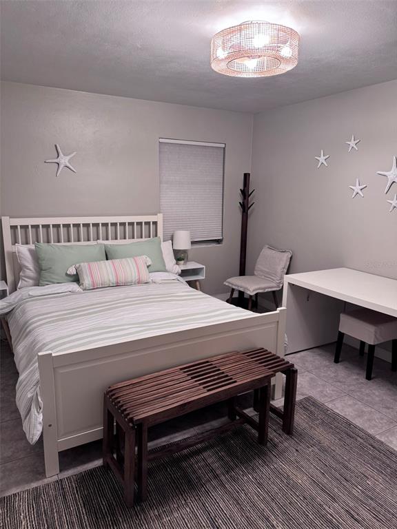 6304 Beechwood Avenue Sarasota, FL 34231 - Photo 24 of 41 a bedroom with a bed a table and painting on the wall