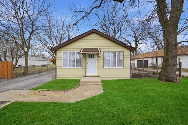 a view of a yard in front of a house with large tree