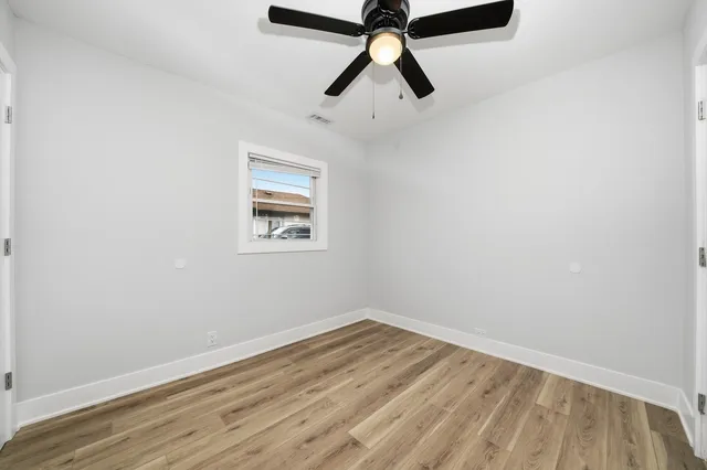 an empty room with wooden floor and ceiling fan