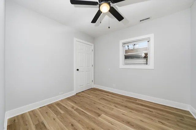an empty room with wooden floor and ceiling fan