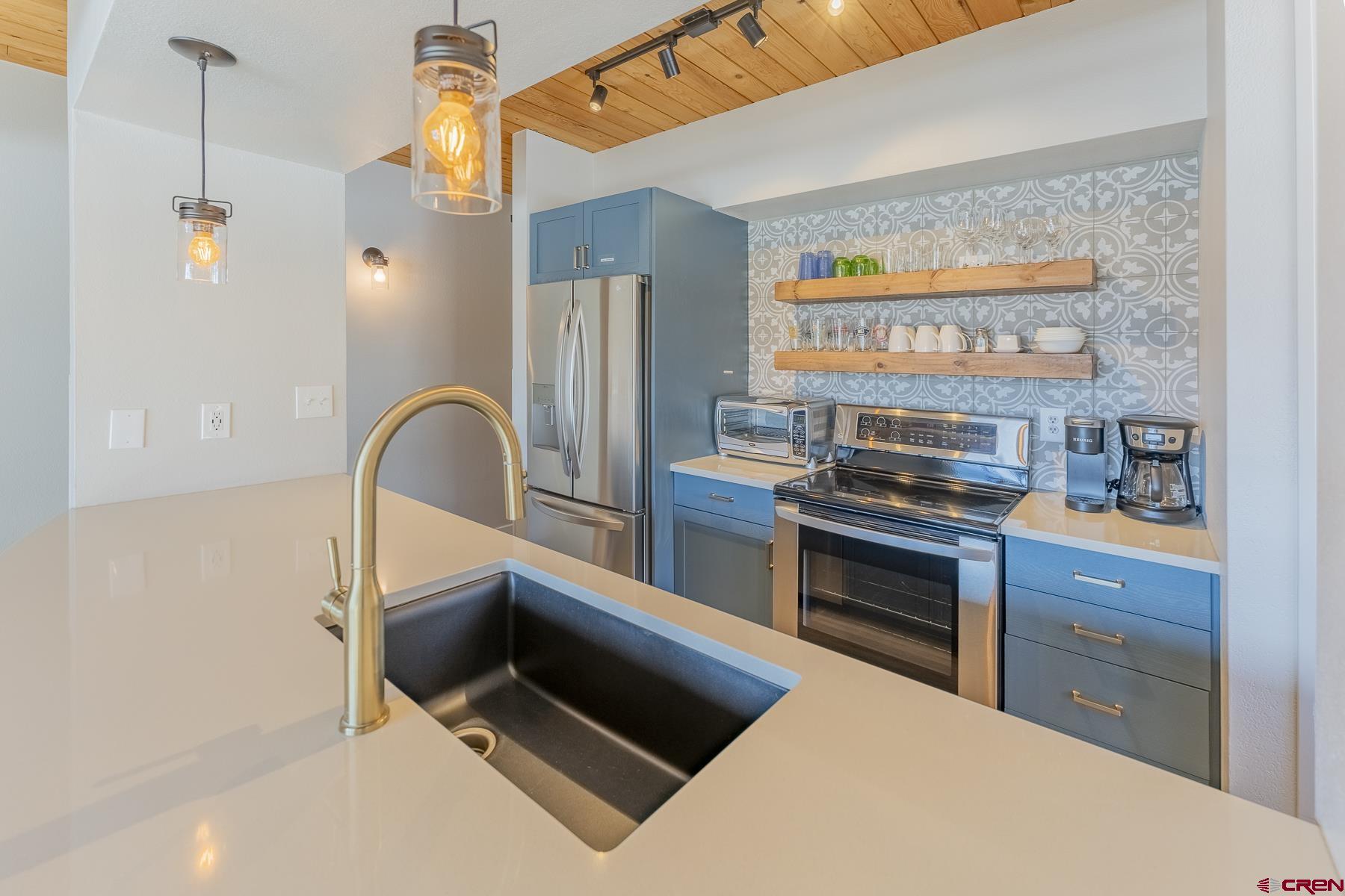 400 Gothic Road, Unit 207 Crested Butte, CO 81225 - Photo 9 of 35 a kitchen with stainless steel appliances kitchen island a stove a sink and a refrigerator