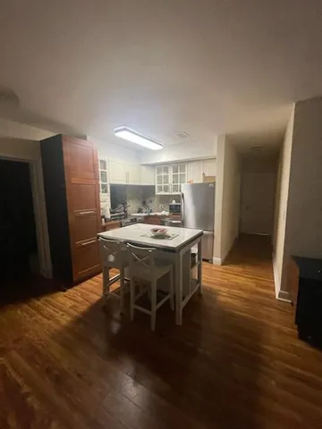 a kitchen with stainless steel appliances kitchen island granite countertop a table chairs and a refrigerator