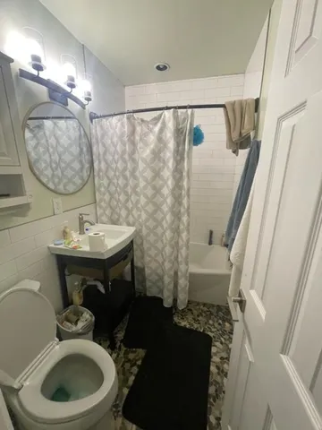 a bathroom with a sink a toilet a mirror and shower