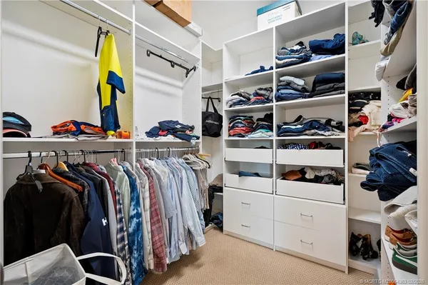 a view of walk in closet with clothes and shoes