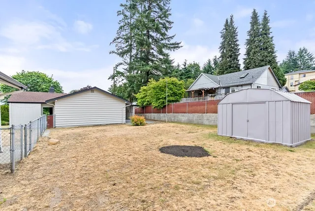 a view of a house with a yard and large tree