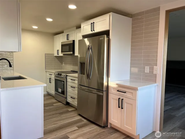 a kitchen with stainless steel appliances granite countertop a refrigerator a stove and a sink