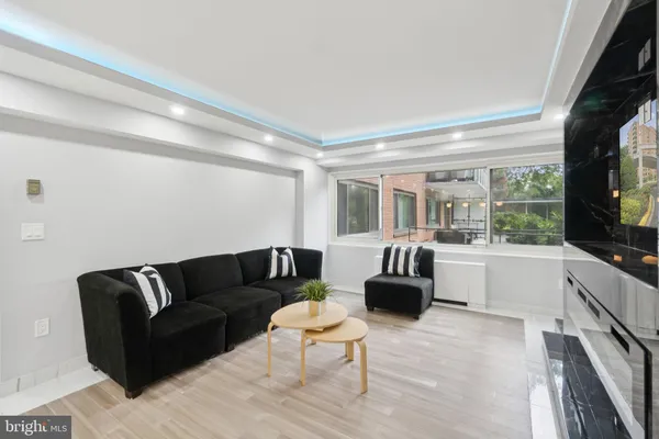 a living room with furniture a flat screen tv and floor to ceiling window