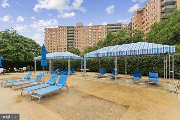 a view of a patio with a table and chairs under an umbrella with large trees