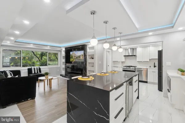 a open kitchen with kitchen island a stove a refrigerator a dining table and chairs with wooden floor