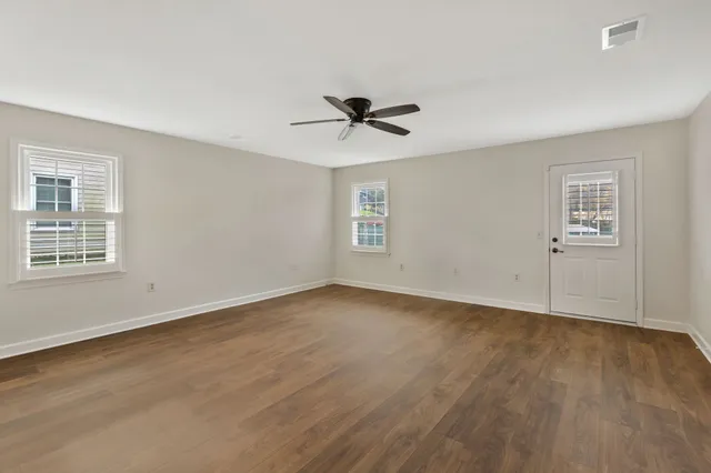 a view of an empty room with a window and wooden floor
