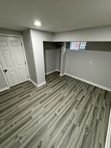 a view of an empty room with wooden floor and closet