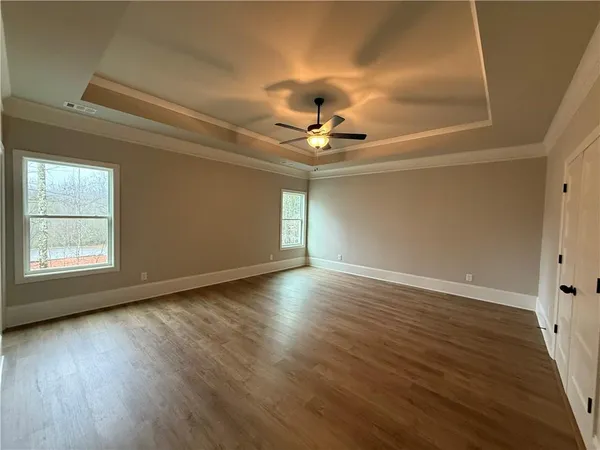 a view of an empty room with window and wooden floor