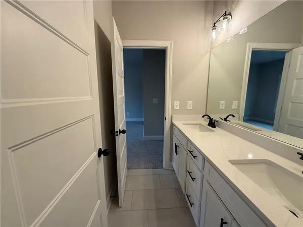 a large white bathroom with a double vanity sink and mirror