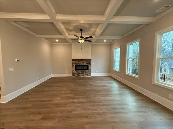 an empty room with windows fireplace and a ceiling fan