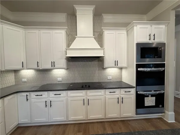a kitchen with granite countertop white cabinets and stainless steel appliances