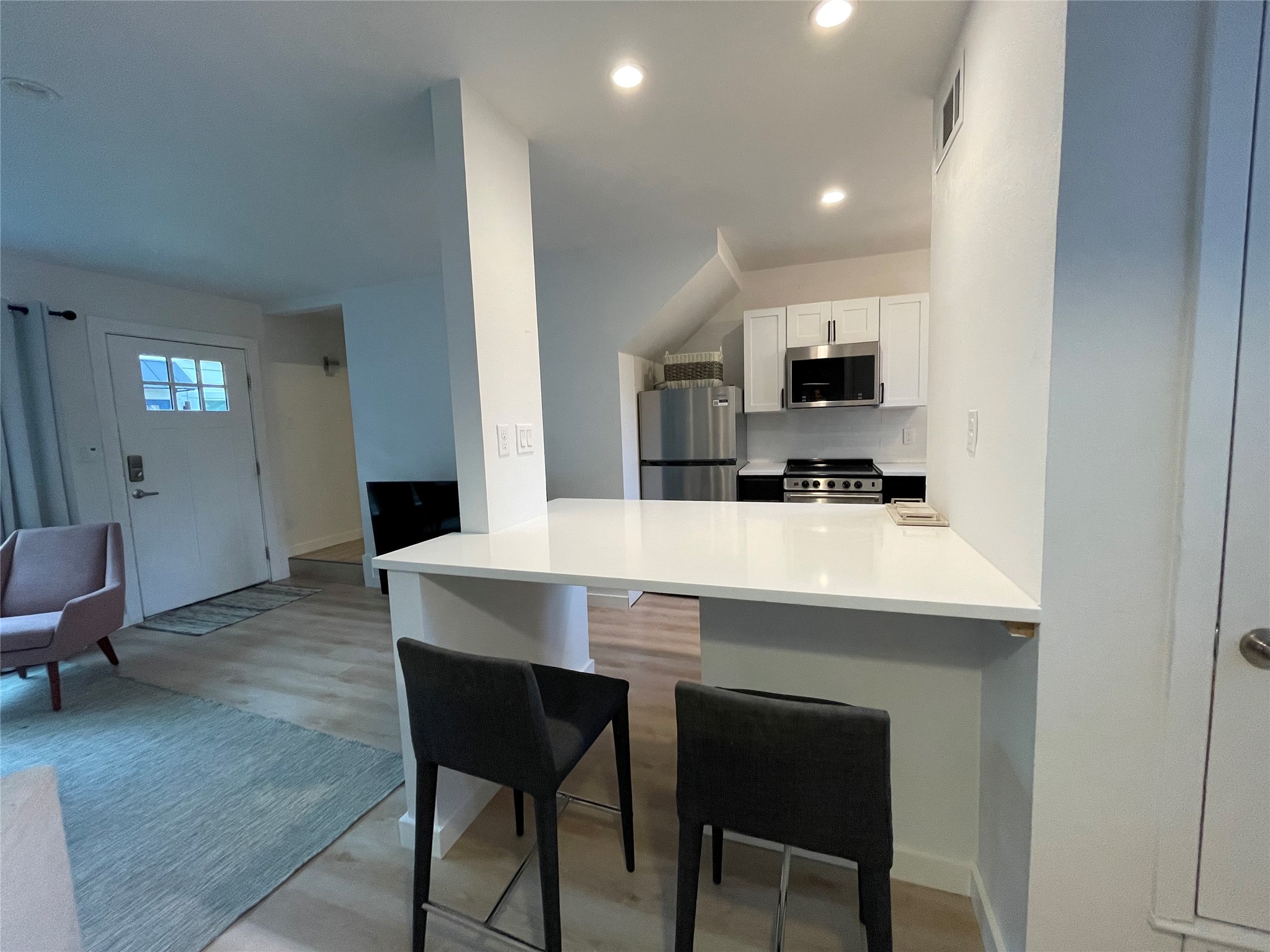 1714 Enfield Road, Unit 102 Austin, TX 78703 - Photo 4 of 15 A well-lit kitchen area features a breakfast bar, stainless steel appliances, and a seamless flow into the adjacent living space.