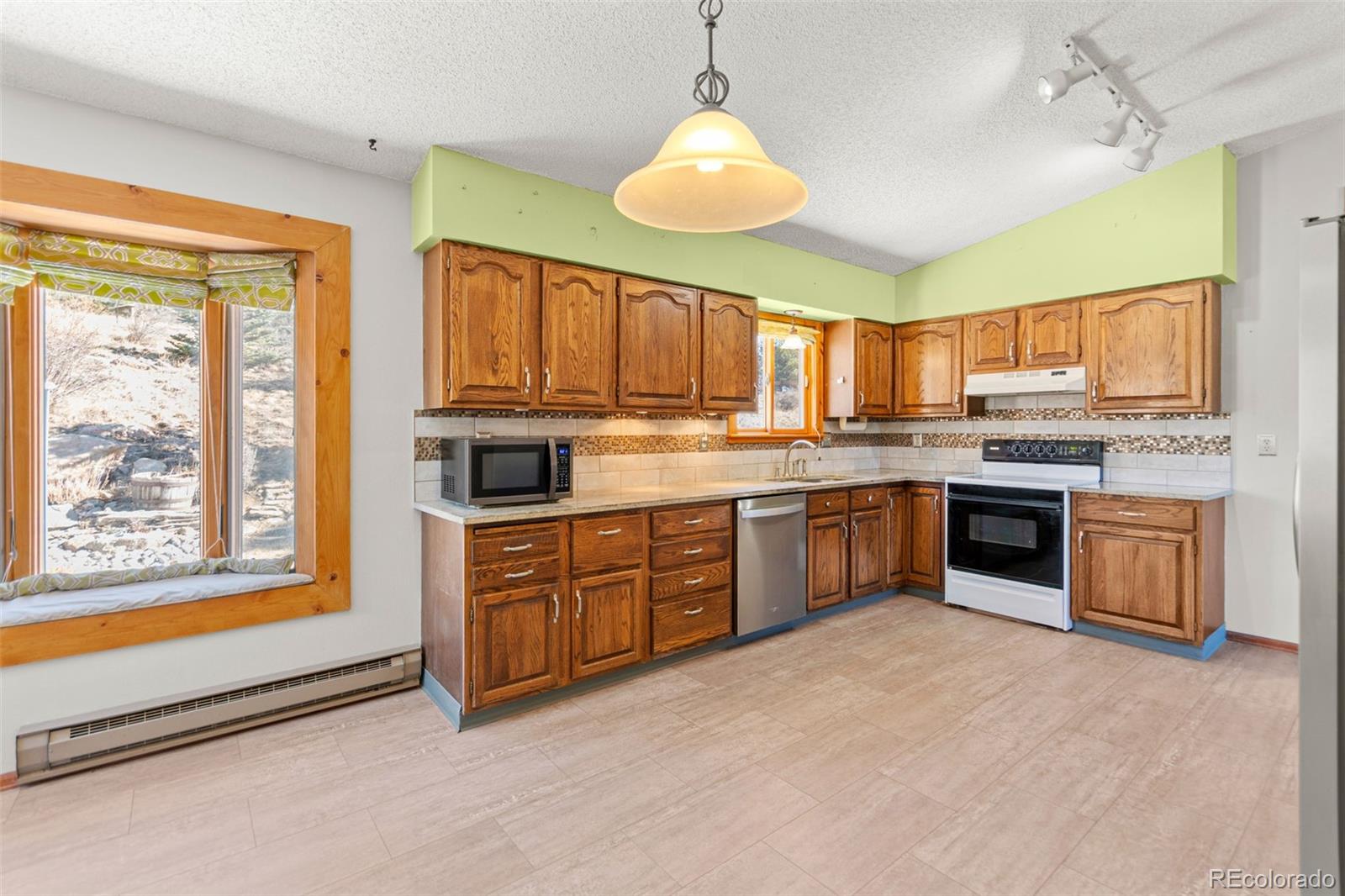 237 Homestead Road Bailey, CO 80421 - Photo 15 of 43 a large kitchen with stainless steel appliances granite countertop a stove granite counter tops and white cabinets