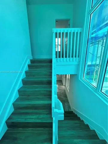 an empty room with wooden floor chandelier fan and windows