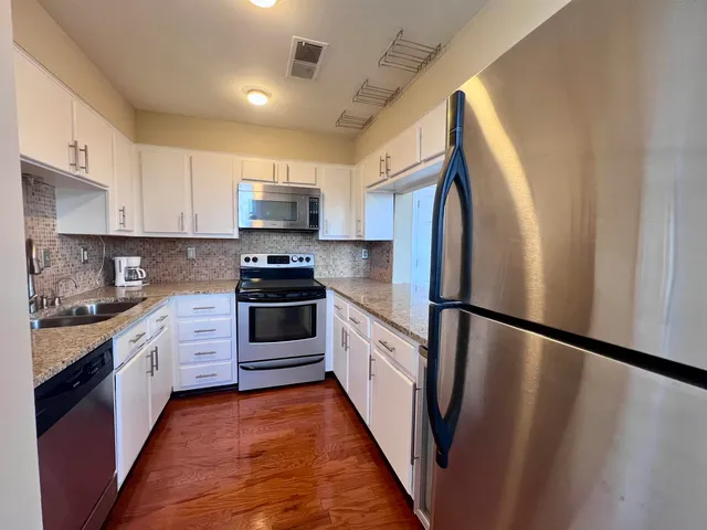 a kitchen with granite countertop a refrigerator stove and sink