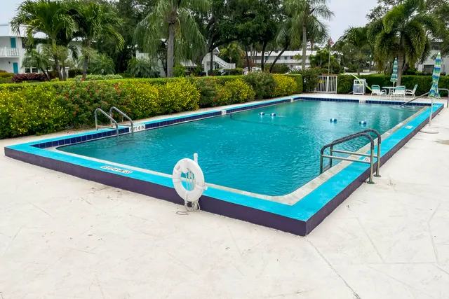 a view of a pool with a bench and trees