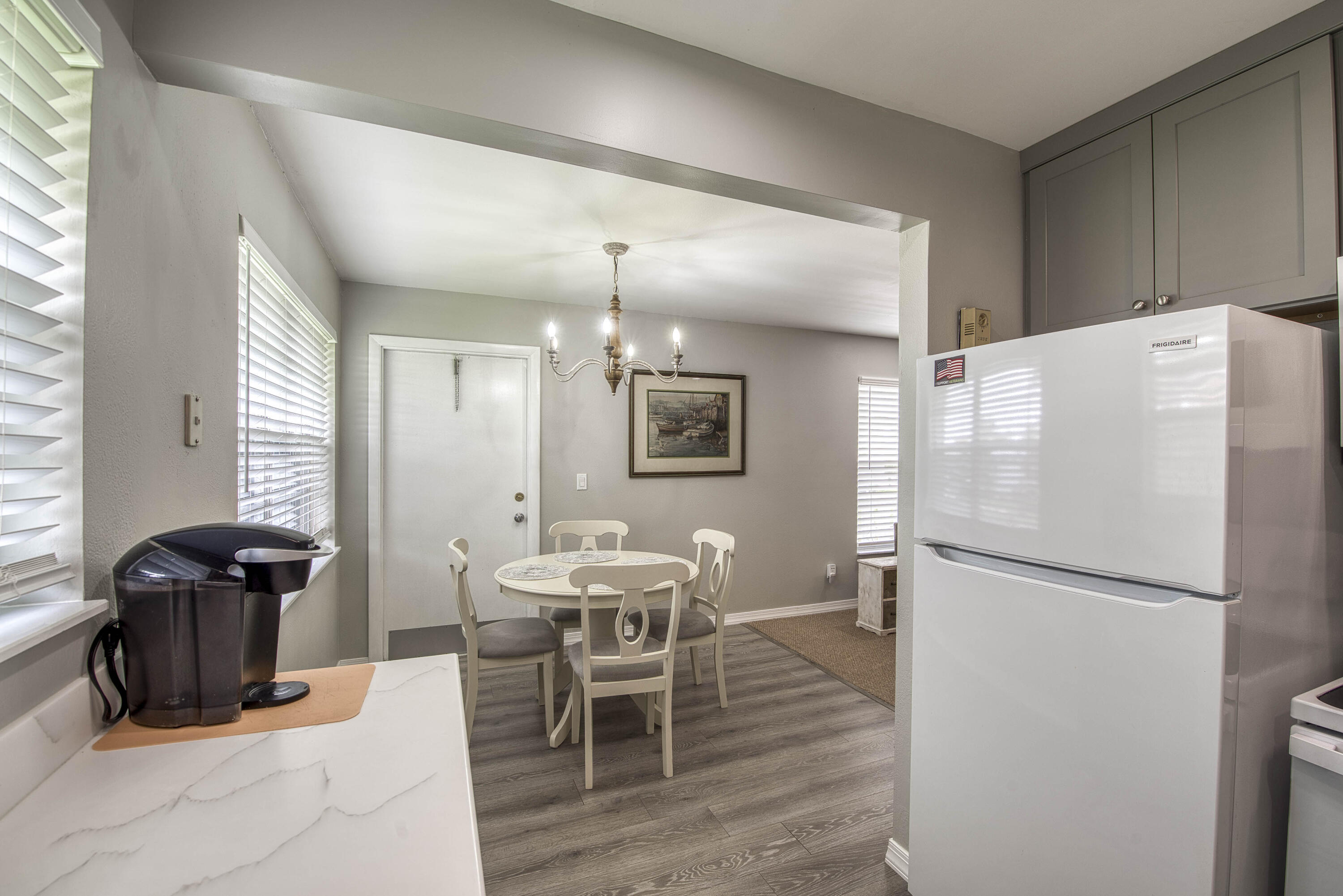 2929 Southeast Ocean Boulevard, Unit 1146 Stuart, FL 34996 - Photo 9 of 19 a kitchen with stainless steel appliances a refrigerator a stove a dining table and chairs with wooden floor