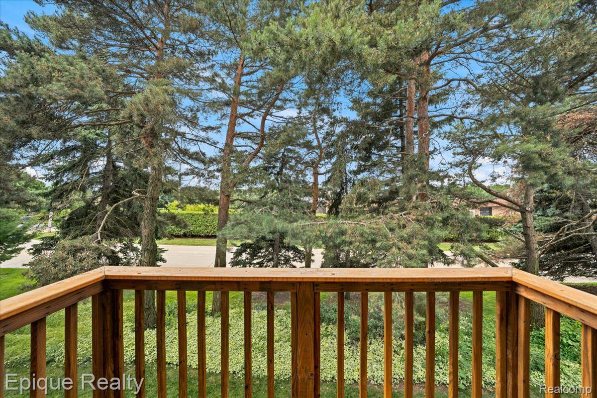 26 Kirks Court Rochester, MI 48309 - Photo 38 of 44 Wooden balcony railing overlooking mature evergreen trees and a paved street
