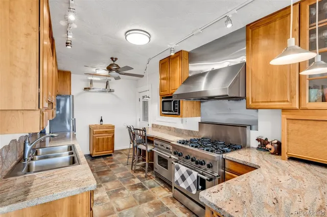 a kitchen with stainless steel appliances granite countertop a sink a stove and a wooden cabinets