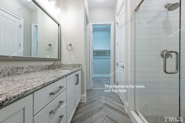 a bathroom with a granite countertop sink two mirror and shower