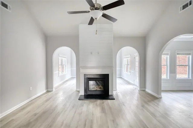 a view of an empty room with fireplace and wooden floor