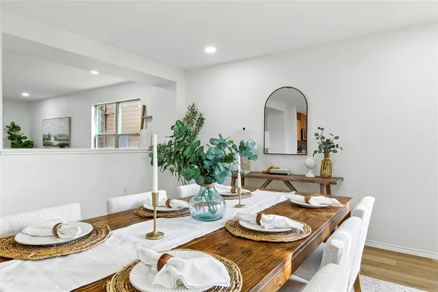 a kitchen with stainless steel appliances kitchen island granite countertop a stove a sink a dining table and chairs with wooden floor