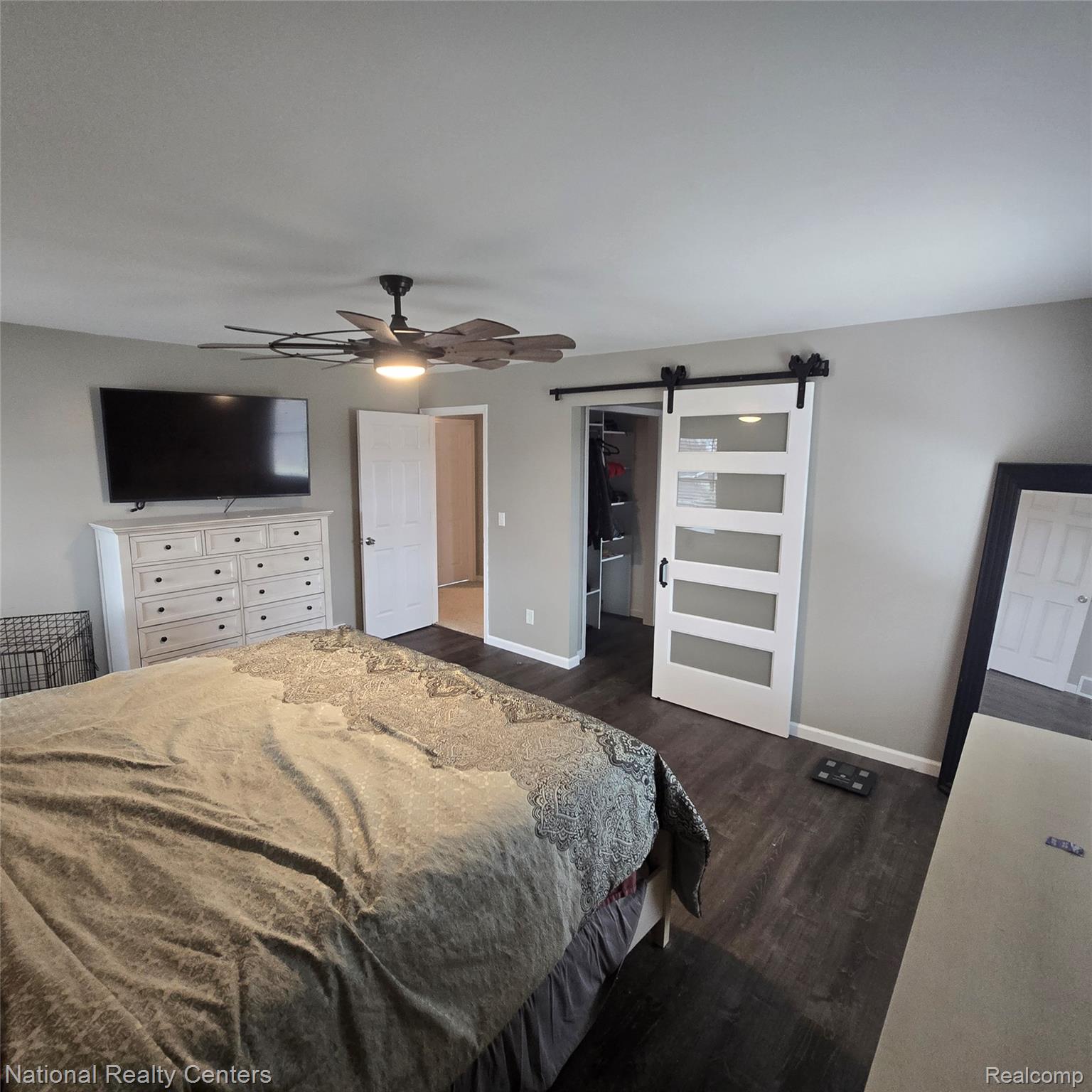 13477 South Horrell Road Fenton, MI 48430 - Photo 10 of 30 Bedroom featuring a barn door, dark wood-type flooring, a spacious closet, and a ceiling fan